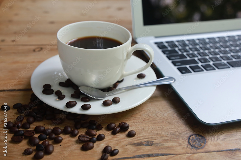Coffee cups and coffee beans Placed next to the laptop on a wooden table Coffee cups and coffee beans Placed next to the laptop on a wooden table