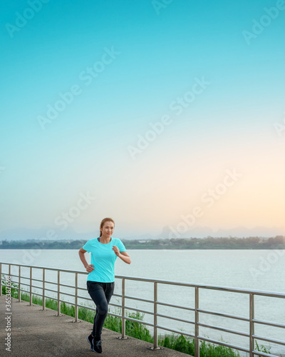 Asian woman is running and jogging an outdoor workout on the riverwalk in the morning for lifestyle health. © ParinPIX