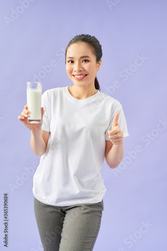Healthy Asian woman drinking a glass of milk thumbs up on purple background