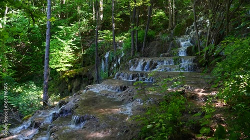 A cascading waterfall in the mountains suround with greenery and trees photo