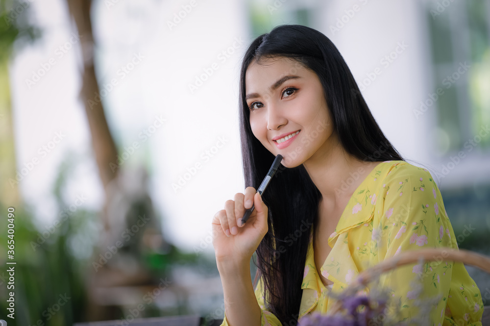young asian woman hand is writing on notepad with a pen in the garden .