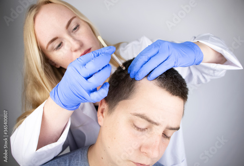 A trichologist doctor drips the serum onto the patient's hair. Treatment of alopecia. Hair loss, alopecia, pruritus, burning head or seborrhea