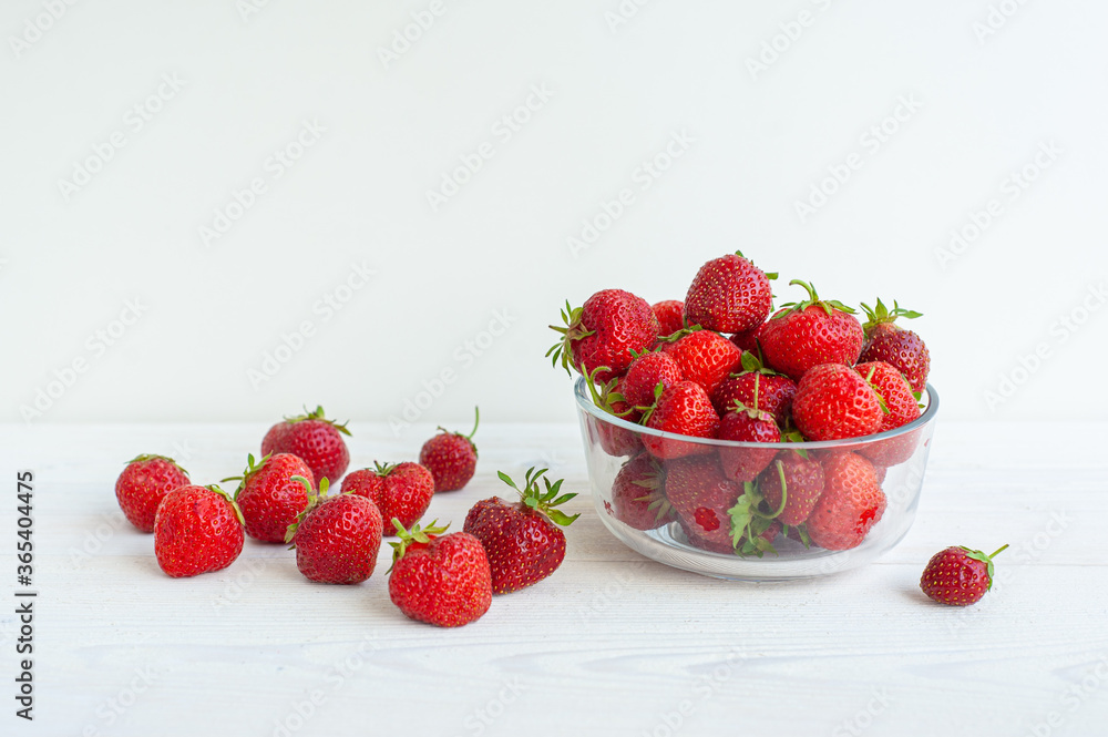 Strawberries on a white wooden background and in a glass bowl. Strawberries on a white wooden background and in a glass bowl.