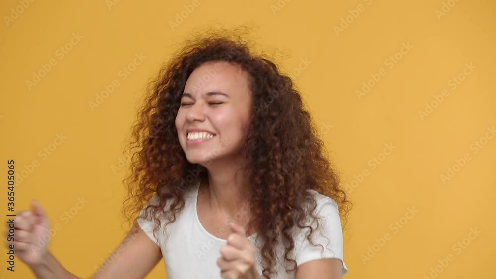 Young african american woman girl in white t-shirt posing isolated on yellow background studio. People lifestyle concept. Looking aside Wait Doing winner gesture say Yes expressive gesticulating hands Young african american woman girl in white t-shirt posing isolated on yellow background studio. People lifestyle concept. Looking aside Wait Doing winner gesture say Yes expressive gesticulating hands