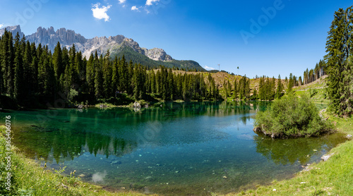 Lake Carezza or Karersee at sunset, wide angle view of scenic landscape in Italy. Dolomites mountains on background, Italian Alps. Nature and travel concepts