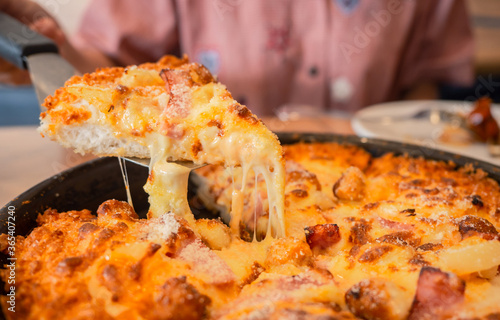 cheese pizza on wooden board. slid pieace growing cheddar cheese, restaurant table. fastfood concept photo