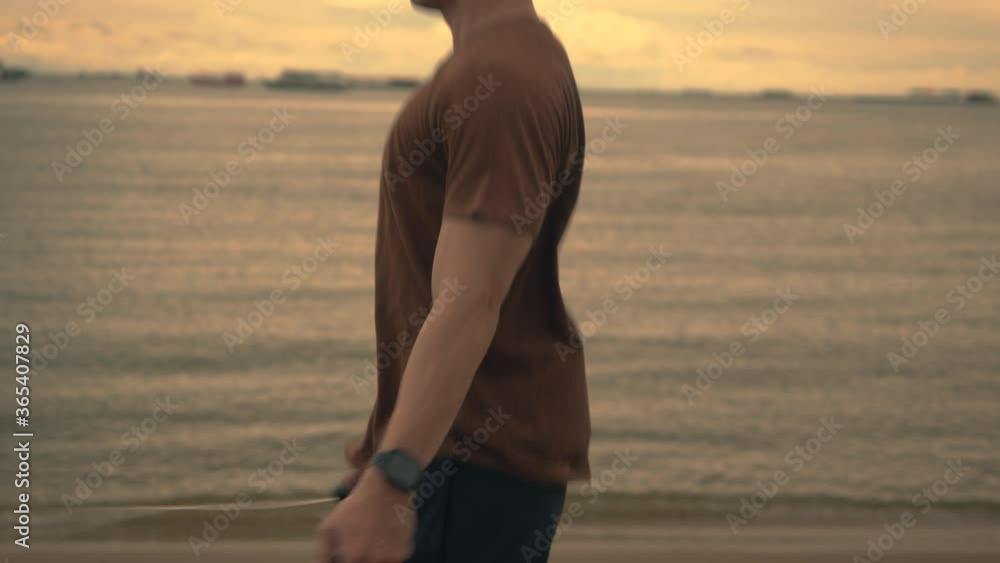 Attractive asian sportsman runner using skipping rope while exercising workout on the beach during a beautiful sunset in summer. Healthy sports lifestyle concept. Attractive asian sportsman runner using skipping rope while exercising workout on the beach during a beautiful sunset in summer. Healthy sports lifestyle concept.