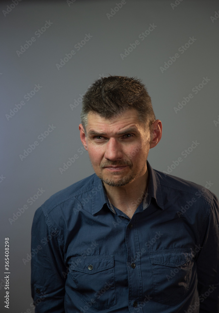 mature actor with bad vision without glasses looks attentively posing for camera against grey studio wall close view mature actor with bad vision without glasses looks attentively posing for camera against grey studio wall close view