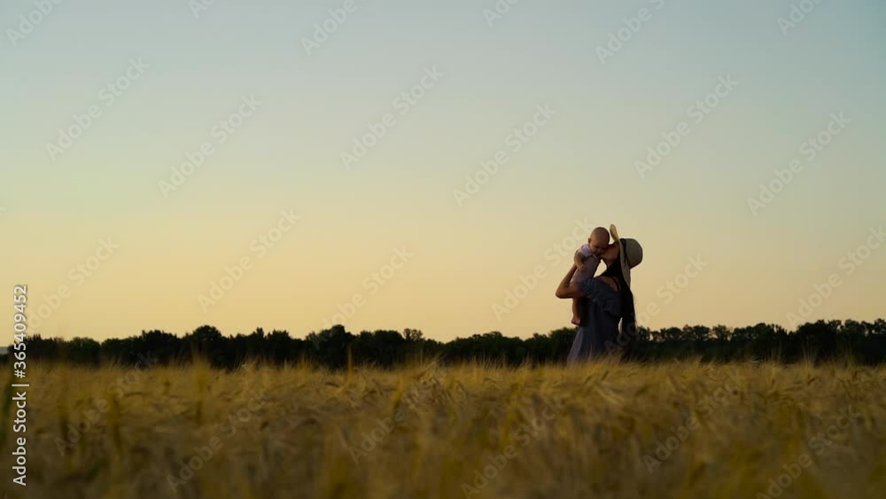Young mother playing with baby in wheat field at sunset Young mother playing with baby in wheat field at sunset