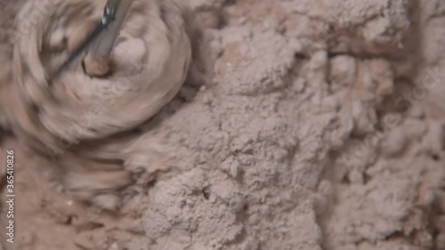 Slow motion pan shot of mixing concrete plaster with electric mixer. spatula and bucket with mortar on the construction site.
