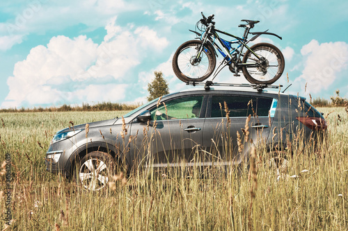 A car is transporting bicycles with a mount on the roof with two Bicycles fastened. Summer vacation with bicycles.