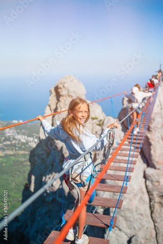Girls crossing the chasm on the rope bridge. Black sea background, Crimea