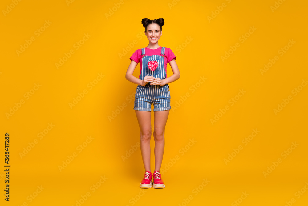 Full length body size view of her she nice attractive lovely pretty cheerful cheery girl holding in hands tasty juicy lollipop isolated on bright vivid shine vibrant yellow color background Full length body size view of her she nice attractive lovely pretty cheerful cheery girl holding in hands tasty juicy lollipop isolated on bright vivid shine vibrant yellow color background