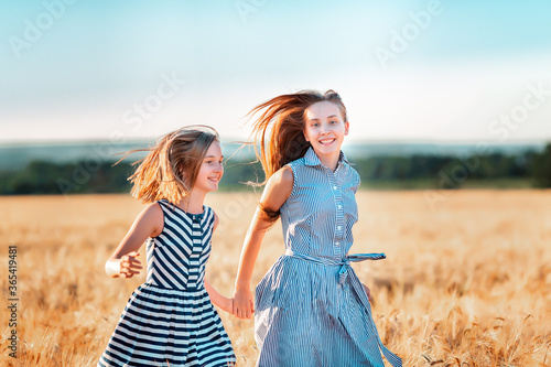 Happy teenage girls running down wheat field