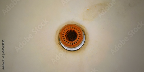 old rusty drain with orange coverage in outdated bath