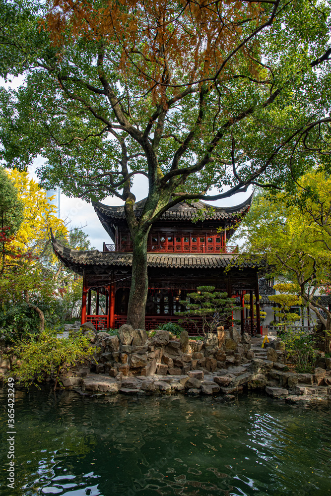 Traditional Chinese architecture in Yu Garden of Shanghai. Ancient pagoda building in garden of autumn trees on pond shore