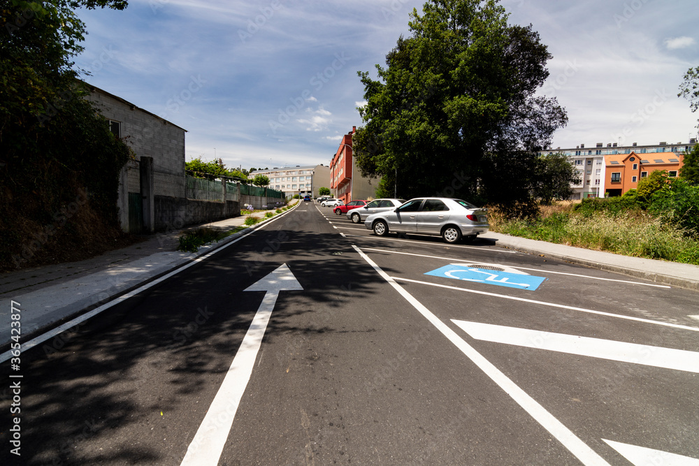 Cars parked in asphalt parking lot and empty spaces in outdoors backrground with disabled parking space