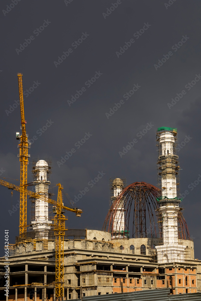 Construction of a mosque. Thunderclouds. The unfinished white mosque shines amid storm clouds. Clouds. Rainbow and Mosque. Crane. Concrete blocks and metal frame. Major construction in the city Construction of a mosque. Thunderclouds. The unfinished white mosque shines amid storm clouds. Clouds. Rainbow and Mosque. Crane. Concrete blocks and metal frame. Major construction in the city