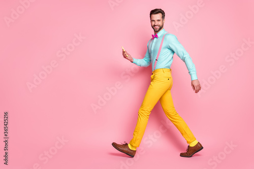Full size profile side photo of positive guy go walk copyspace use smartphone enjoy leisure time blogging wear shirt bow tie pants shoes isolated over pastel color background