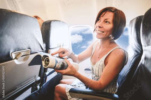 Caucasian beautiful woman like passenger siting near window inside airplane and talking with stewardess