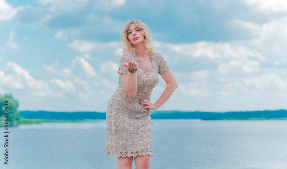 Nice blonde romantic plus size woman in knitted fashionable golden dress at seafront, fashion concept, fancy clothes Nice blonde romantic plus size woman in knitted fashionable golden dress at seafront, fashion concept, fancy clothes