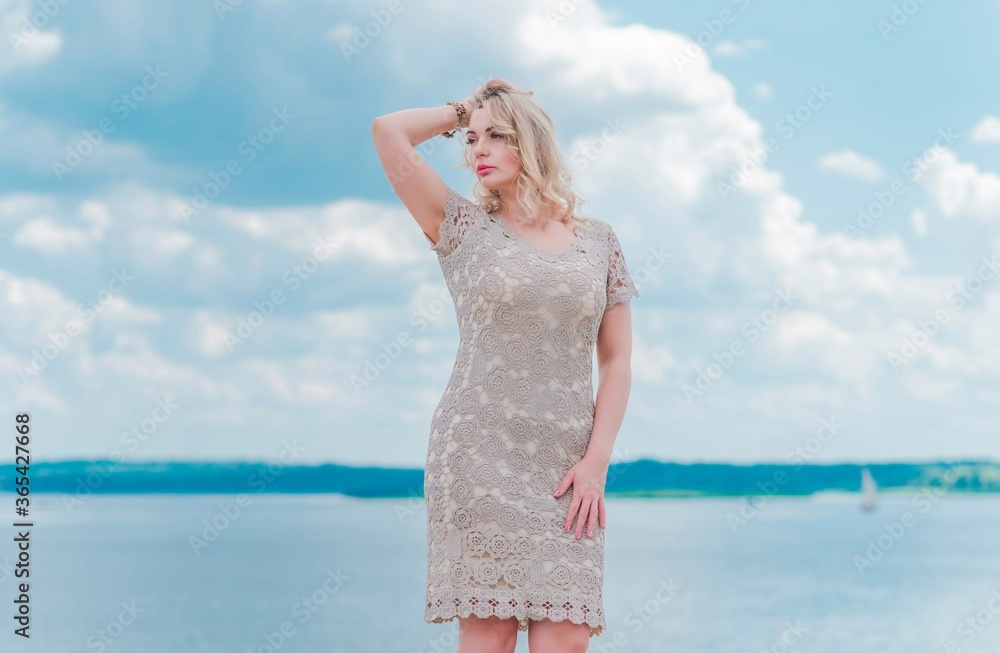 Nice blonde romantic plus size woman in knitted fashionable golden dress at seafront, fashion concept, fancy clothes Nice blonde romantic plus size woman in knitted fashionable golden dress at seafront, fashion concept, fancy clothes