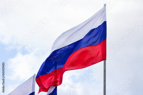 Russian flag waving against the blue sky and white clouds. Symbol of Russia, russian authority concept.