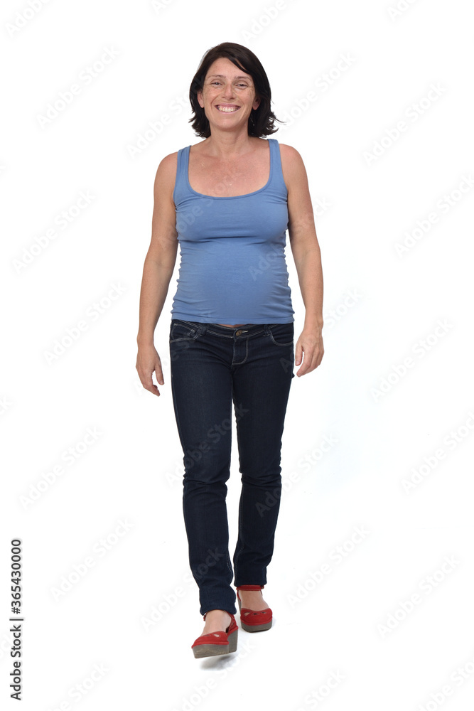 Fototapeta premium full portrait of a woman walking and with casual clothes on white background, front view