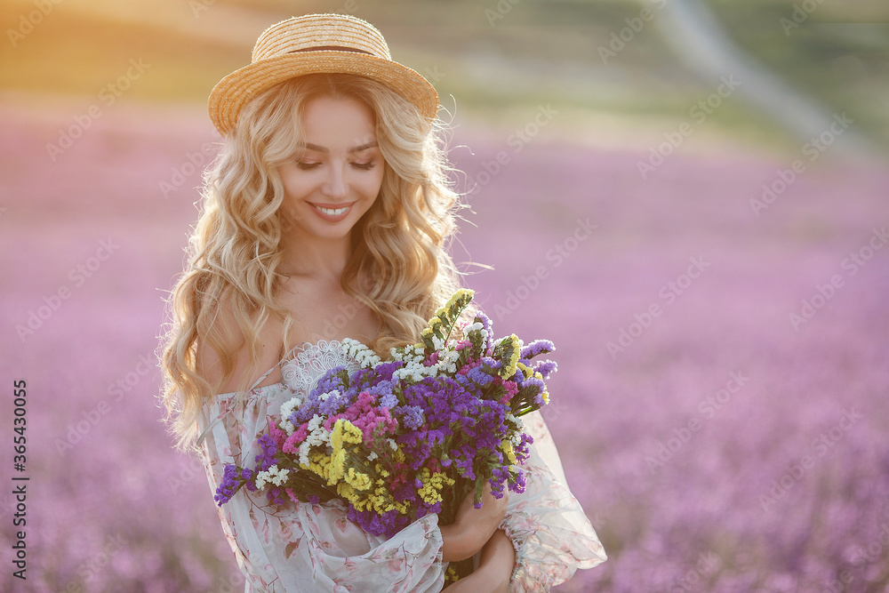 Fototapeta premium pretty blonde woman running away in lavender field. woman in long dress and straw hat having fun in flowers of lavender