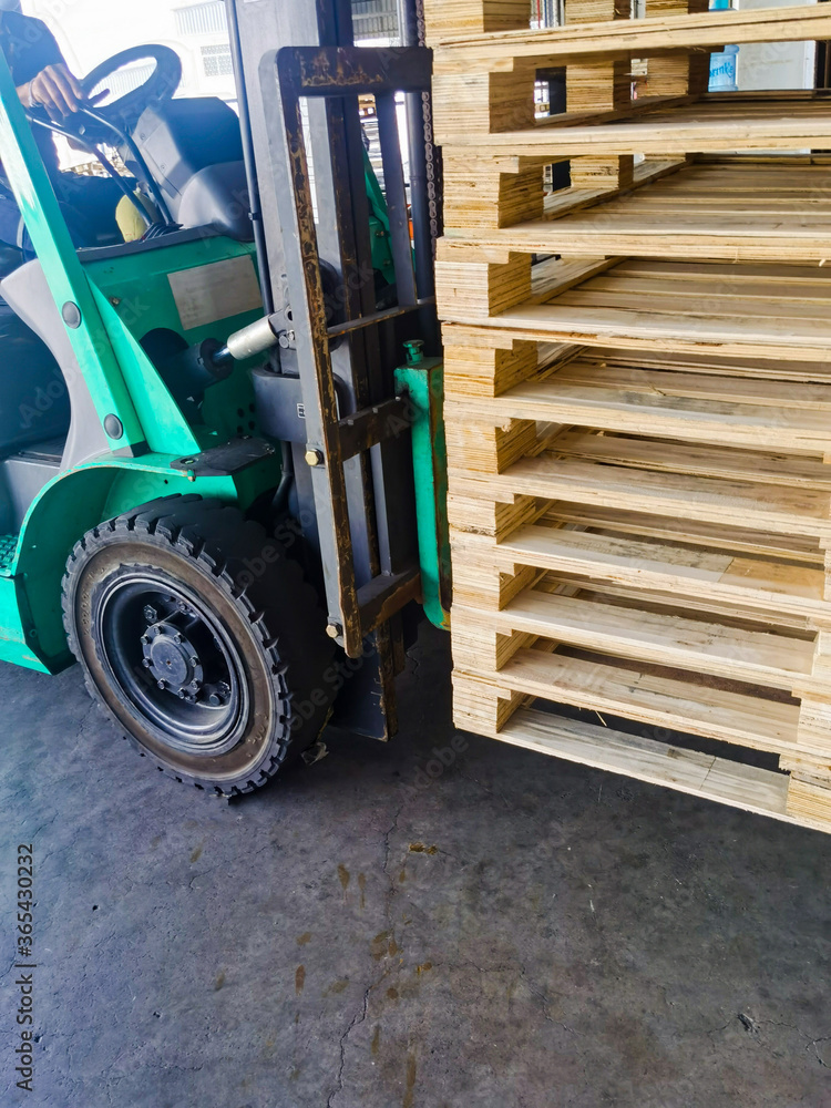 Naklejka premium Worker driving forklift to loading and unloading wooden pallets from truck to warehouse cargo storage, shipment in logistics and transportation industrial, wood pallets stack