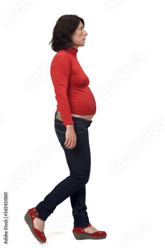 side view of full portrait of a pregnant woman with casual clothes walking on white background,