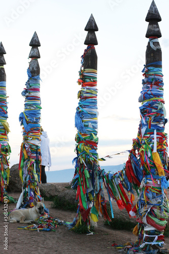  Olkhon / Russia - 27 June 2019: Shaman rock at lake Baikal with the sunset light. The bars of the hitching post tied with ribbons on Olkhon island. Beautiful summer landscape.