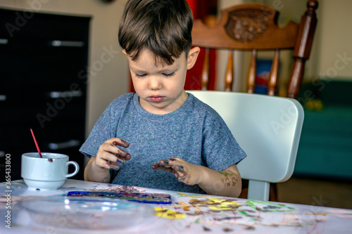 Smiling little boy is about to make finger print on colorful paper. Happy beautiful child playing with colors. ..Education, school, art and painting concept. Copy-space. ....