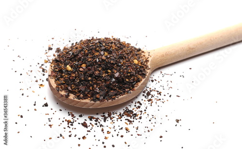 Aromatic spicy chili pepper flakes, dry ancho chili pile with wooden spoon isolated on white background