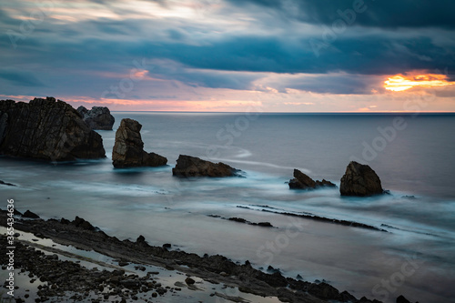 Long exposure over calm sea with rocks during a cloudy sunset