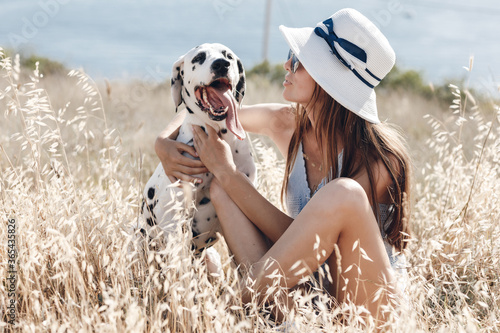 Woman with a dog dalmatian in a field in summer