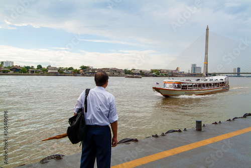 Photography man on a pontoon waiting for the speed boat on the Chao Phraya River in Bangkok,