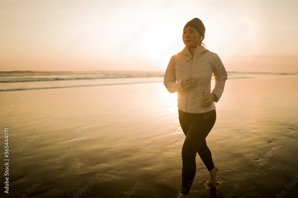 Asian girl running on the beach - young attractive and happy Chinese woman doing jogging workout at beautiful beach enjoying fitness and healthy runner lifestyle Asian girl running on the beach - young attractive and happy Chinese woman doing jogging workout at beautiful beach enjoying fitness and healthy runner lifestyle