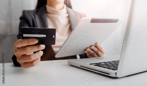 businesswoman hand using smart phone, tablet payments and holding credit card online shopping, omni channel, digital tablet docking keyboard computer at office in sun light