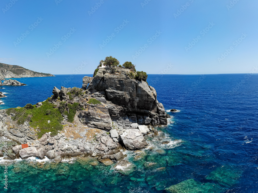 The church of Agios Ioannis on the Mamma Mia Cliff on the island of Skopelos, shaken by the blue Mediterranean sea.