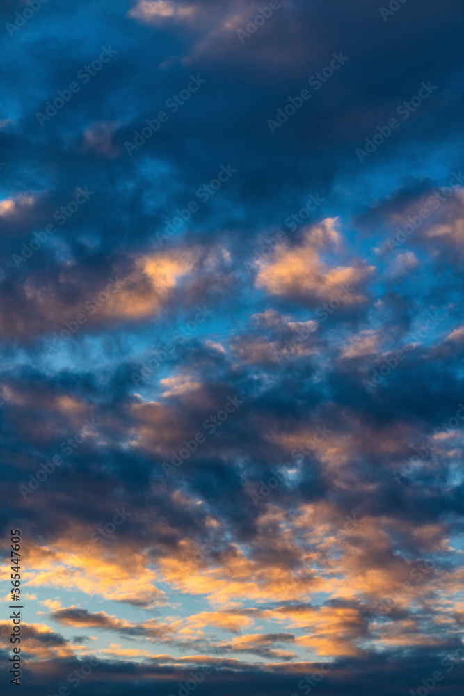 Beautiful clouds in blue sky, illuminated by rays of sun at colorful sunset to change weather. Soft focus, motion blur abstract meteorology background.