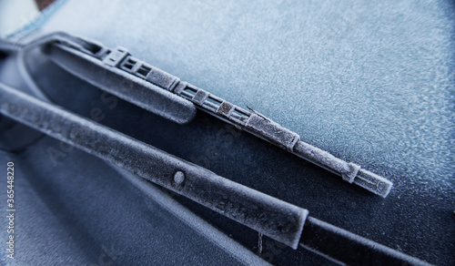 A frozen icy cold textured car in winter on a freezing morning, frozen windscreen. frozen solid in the windy freeze environment. frosty windows and black ice on the road. minus degrees.