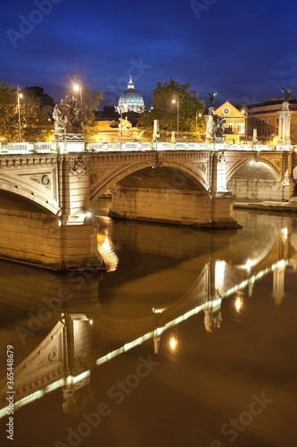 Blick auf die Kuppel des Petersdom und einer Brücke bei Nacht zur blauen Stunde mit Spiegelung