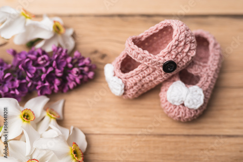 Small, hand-made shoes for a newborn baby. Needlework. Composition on oak boards. View from above. Flat Lying picture.