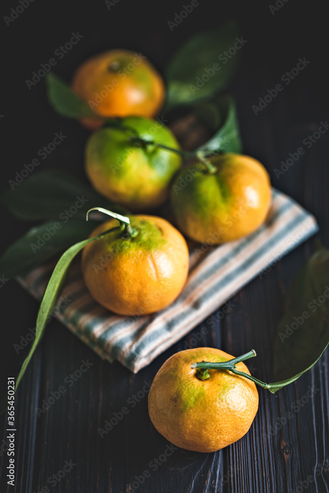 Tangerines with leaves on an old fashioned country table. Selective focus. Vertical. Tangerines with leaves on an old fashioned country table. Selective focus. Vertical.
