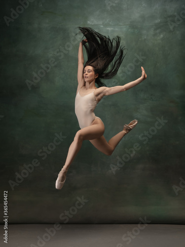 Target, achievement. Graceful classic ballerina dancing on dark studio background. Pastel bodysuit. The grace, artist, movement, action and motion concept. Looks weightless, flexible. Fashion, style.