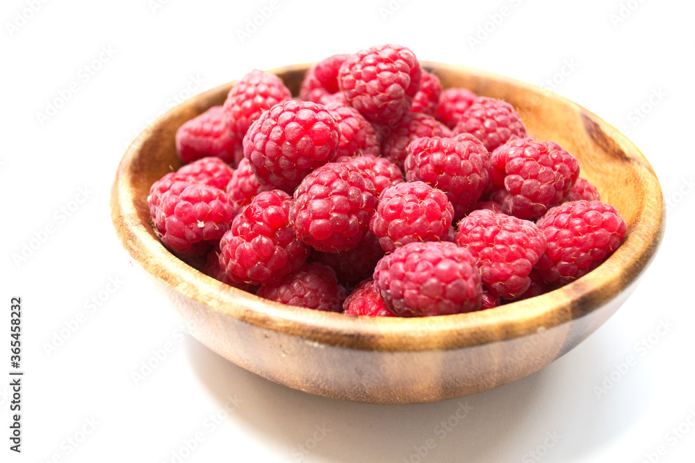 heap of fresh red raspberry in wooden plate isolated on white background heap of fresh red raspberry in wooden plate isolated on white background