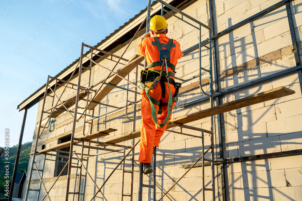 Obraz premium Construction worker wearing safety harness belt during working at high place at construction site.
