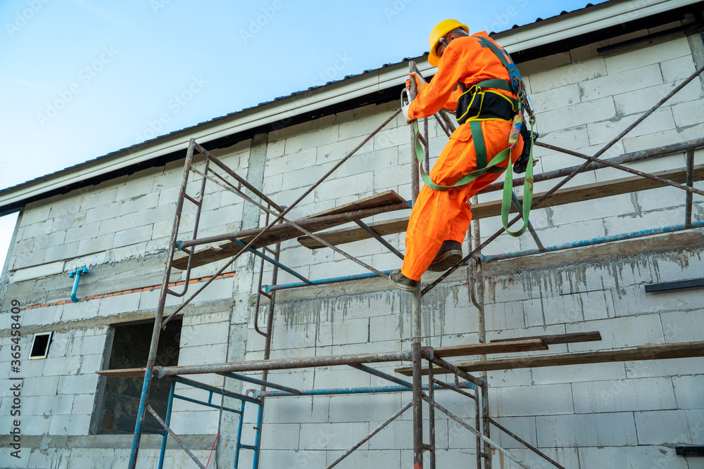 Fototapeta premium Construction worker wearing safety harness belt during working at high place at construction site.