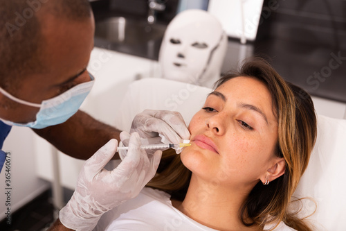 Attractive Latina receiving injections for face skin tightening at aesthetic cosmetology clinic